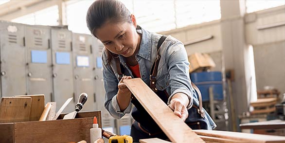 carpenter with medical coverage inspects work in woodshop